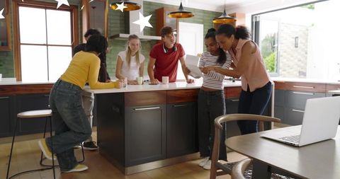 Diverse team collaborating around modern kitchen island with laptop and documents