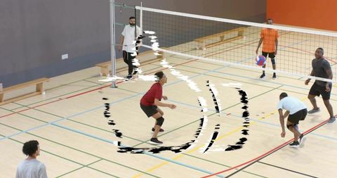 Indoor volleyball team practicing dynamic pass and defensive positioning on hardwood court