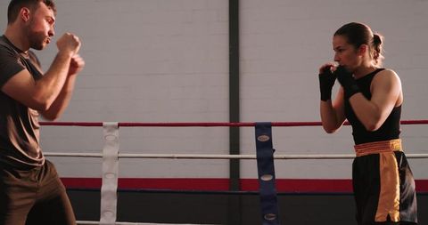 Male and female boxers sparring in ring, trading jabs and building strength