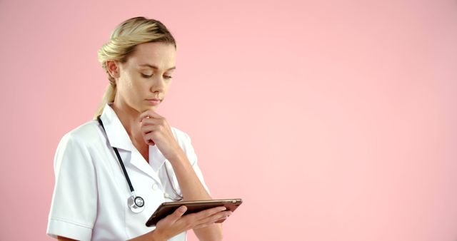 Young Nurse Thinking and Using Tablet Against Pink Background - Download Free Stock Images Pikwizard.com