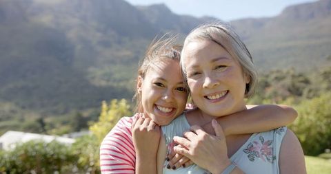 Smiling Grandmother and Granddaughter Embracing in Scenic Outdoor