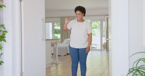 Cheerful woman waving at home entrance