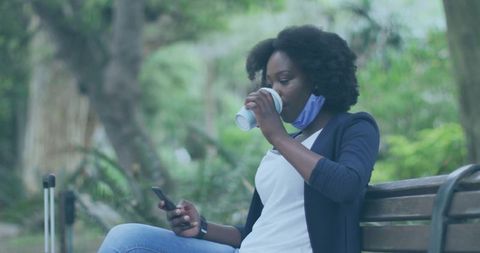 Woman Enjoying Coffee Break in Park Texting on Smartphone