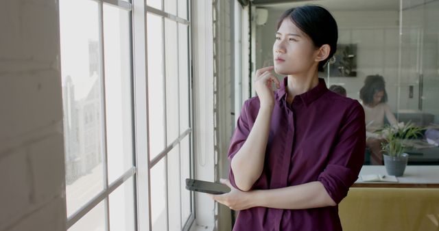 Thoughtful Businesswoman Holding Smartphone at Office Window - Download Free Stock Images Pikwizard.com