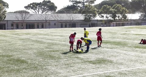 Soccer players aiding injured teammate on field during game