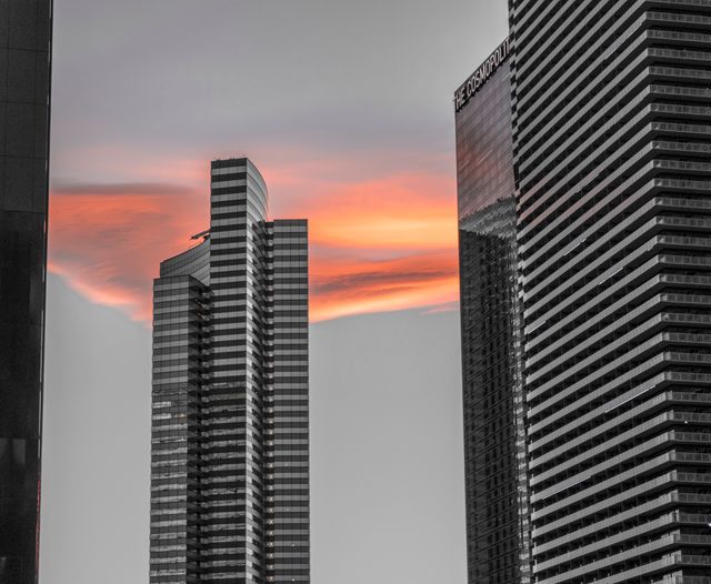 Contrasted stark modern skyscrapers with a warm, dramatic sunset backdrop. Great for urban living, business or corporate themes, city development projects and real estate promotions.