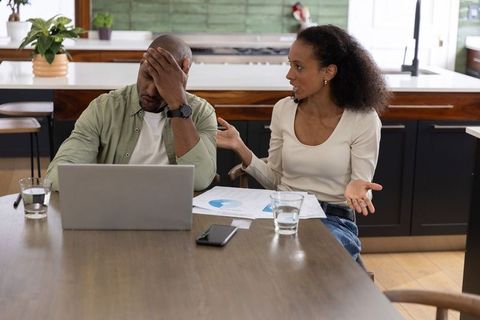 Couple Discussing Household Finances at Kitchen Table, Stress Over Bills and Budgeting