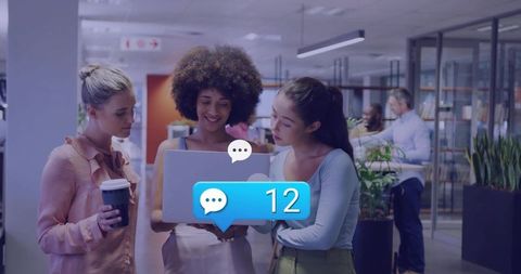 Three colleagues collaborating around laptop with message notification 12 in modern office