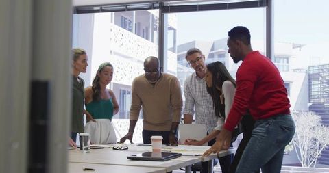 Diverse team reviewing project plans around conference table in bright modern office