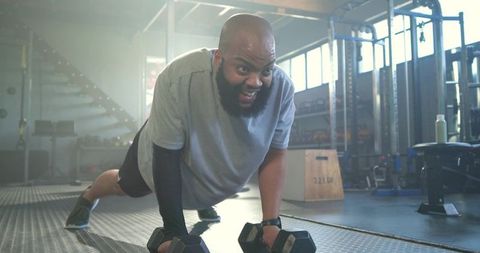 African American man planking on hex dumbbells in gym for strength and endurance training
