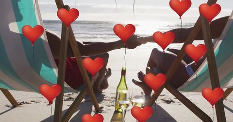 Romantic Beach Couple Relaxing with Wine and Heart Balloons
