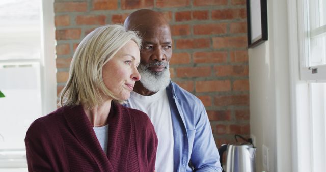 Happy senior diverse couple in kitchen, looking through window and embracing - Download Free Stock Photos Pikwizard.com