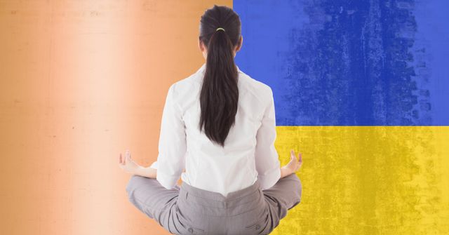 Businesswoman meditating against vibrant Ukraine flag representing stress relief and workplace wellness. The settings emphasize international relations and peace. Useful for topics on global issues, promoting mental health in the workplace, and corporate support for international causes.