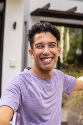 Energetic young man embracing outdoors near modern home