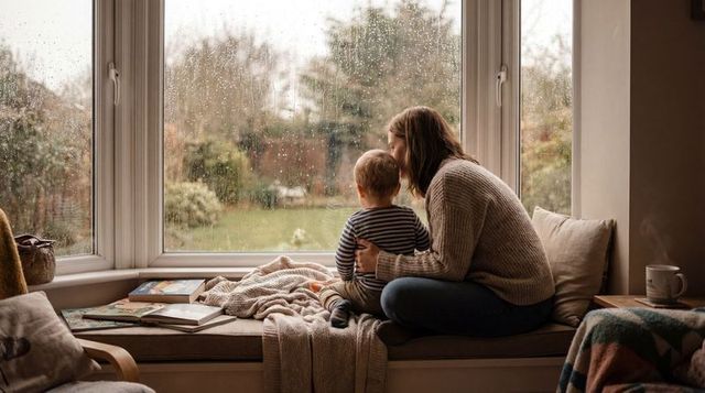 Mother and toddler sharing cozy rainy-day window seat, reading nook quiet bonding moment