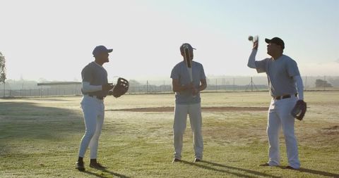 Morning Baseball Teammates Practicing Tossing and Bat Drill on Dewy Field for Team Training