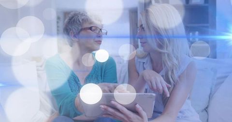 Sharing tablet and connecting generations on cozy living room sofa with bokeh light overlay