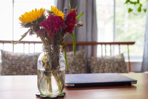 Colorful sunflower and floral arrangement in mason jar on table
