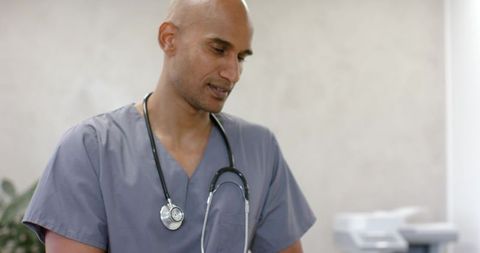 African american clinician examining chart in clinic wearing gray scrubs and stethoscope