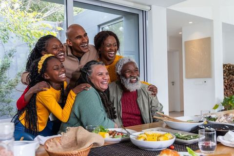 Multigenerational african american family laughing and dining together in bright modern home