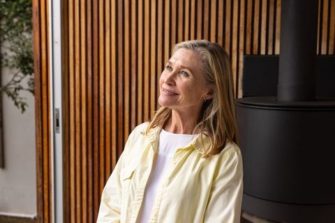 Senior woman relaxing by stylish wooden slatted wall indoor