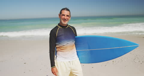 Smiling Senior Man at Beach Holding Surfboard on Sunny Day