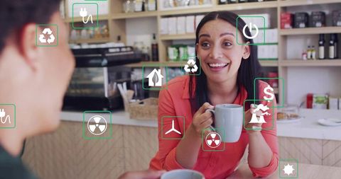 Smiling woman holding mug and chatting in cafe with augmented reality sustainability icons
