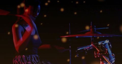 Female drummer performing under red and blue stage lights with motion bokeh haze