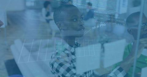 Professional analyzing data on glass board in modern office environment