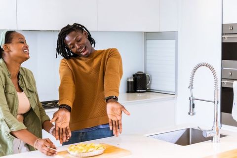 Two african american women presenting homemade pie at bright modern kitchen island