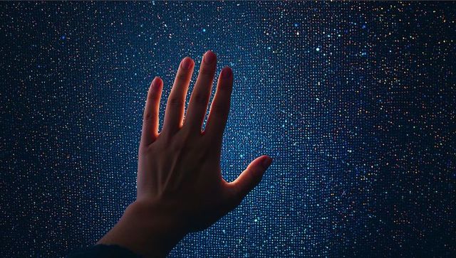 Reaching hand touching vibrant led pixel grid with blue glow and multicolor sparkle