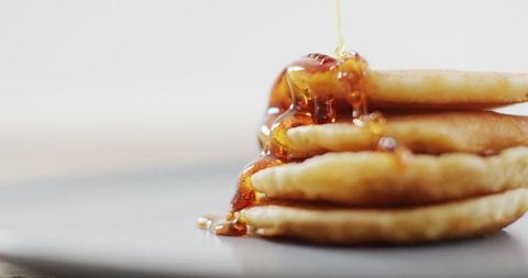 Stack of pancakes drizzled with maple syrup on white plate