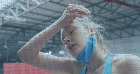 Female athlete pressing forehead, panting after workout, wearing mask with code overlay