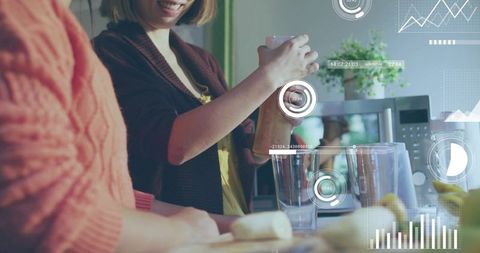 Mother pouring smoothie into glass while family member chopping banana on smart kitchen counter