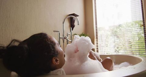 Relaxed woman with vitiligo enjoying bubble bath