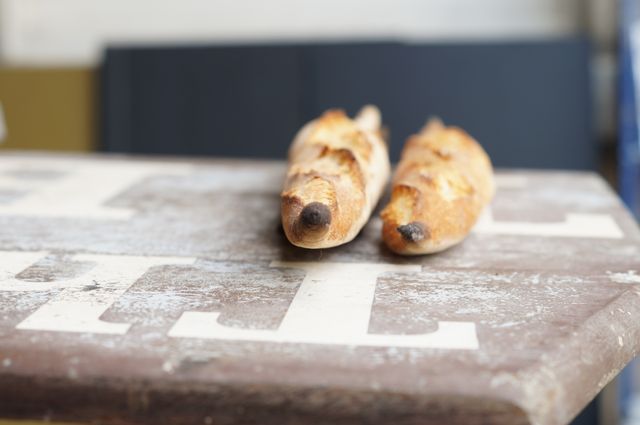 Close-up of freshly baked French baguettes resting on a vintage wooden table. Great for culinary blogs, bakery promotional materials, and gourmet food advertisements.