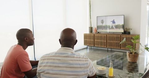 Father and son watching tv and enjoying leisure time at home