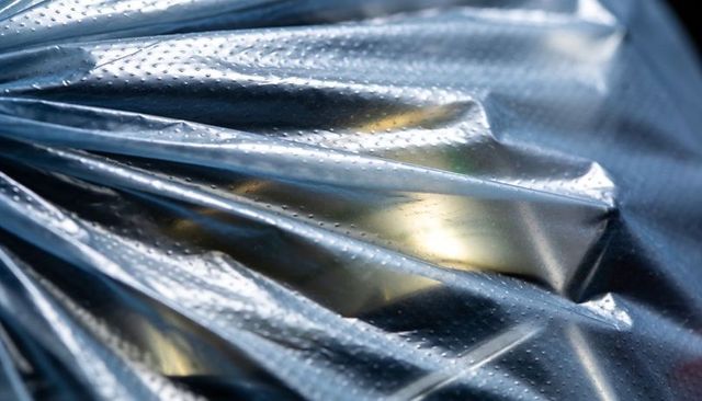 Glinting silver foil with radial pleats and micro-dotted texture for abstract backgrounds