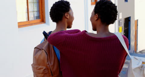 Twin Sisters Smiling While Strolling in City Street
