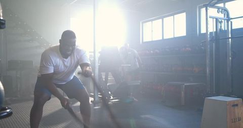 African american men training with battle ropes in industrial gym sunlit intense workout