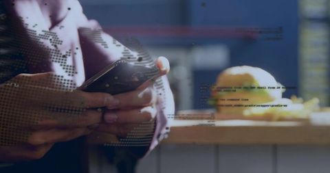 Holding smartphone and scrolling with digital globe, code overlay and pastry on café counter