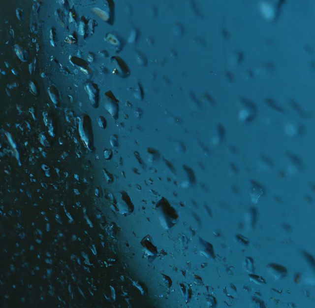Image of close up of multiple rain drops on blue surface. Nature, rain, water and weather concept.