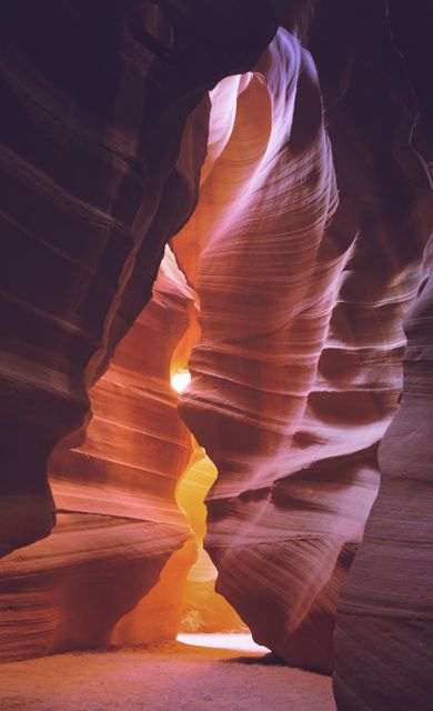 Sunlight filters through the narrow opening of Antelope Canyon, highlighting the curved, smooth sandstone walls. The natural erosion has created stunning formations with rich orange and red hues. Ideal for use in travel brochures, geological exhibits, and nature-themed publications.
