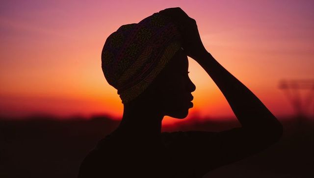 Silhouette of Woman in Headwrap at Sunset with Vibrant Gradient Sky