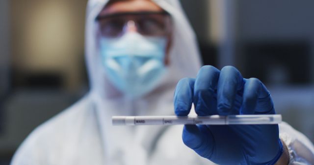 Caucasian male medical worker wearing protective clothing mask and gloves holding dna swab in lab. healthcare, medical research technology and hygiene during coronavirus covid 19 pandemic.