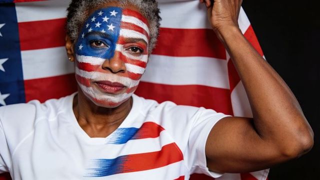 Senior african american woman holding american flag with face painted stars and stripes