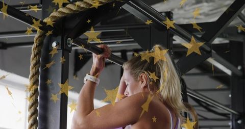Blonde woman doing pull-up on steel gym rig with rope and smartwatch, gold star overlay