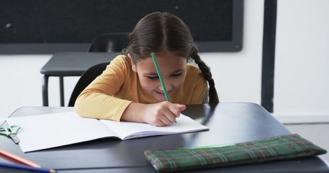 Young Biracial Girl Writing in Classroom with Green Pencil - Download Free Stock Images Pikwizard.com