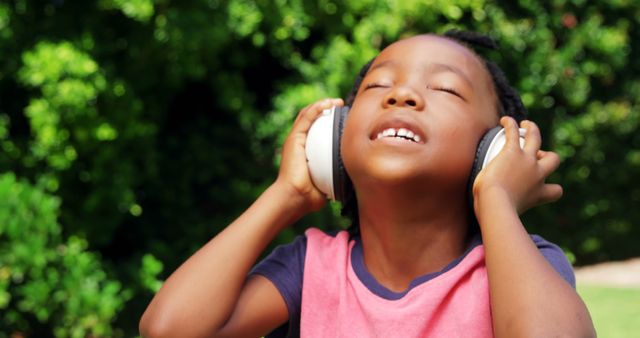 A young African American boy enjoys music on his headphones, with copy space. His expression conveys the joy and freedom of immersing in his favorite tunes on a sunny day.