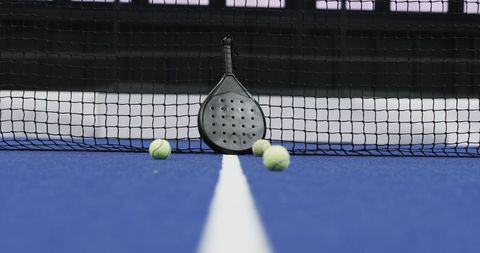 Padel Racket and Balls on Blue Court Highlighting Vibrant Sports Theme